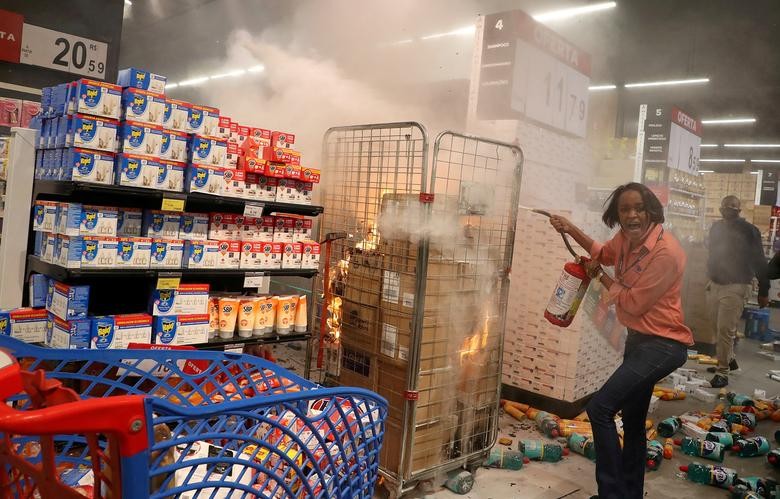 A woman puts out a fire at a vandalized Carrefour store during a march in Sao Paulo on National Black Consciousness Day and in protest against the death of Joao Alberto Silveira Freitas, a Black man beaten to death at a market in Porto Alegre, Brazil, November 20, 2020. REUTERS/Amanda Perobelli